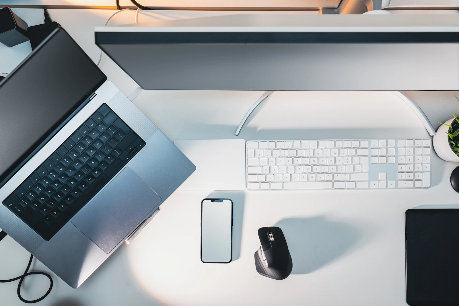 Mesa de trabalho com notebook, monitor, teclado e celular
